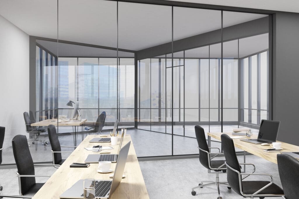 Modern office interior featuring large windows and a spacious desk, highlighting the importance of timely office fit-outs.